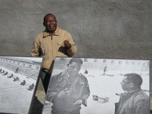 A guide explains the experiences of Nelson Mandela and Walter Sisulu (left and right in the poster) at Robben Island prison. Photo by Barbara Borst